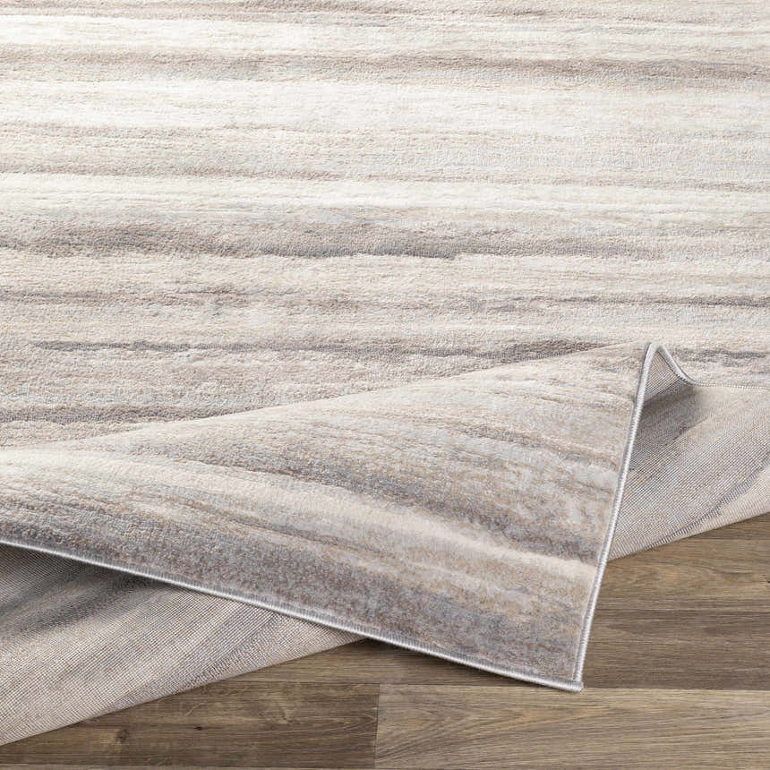 Close-up of the Fombell Abstract Striped Area Rug. Features charcoal, gray, tan, and white tones with a subtle striped pattern. Fold