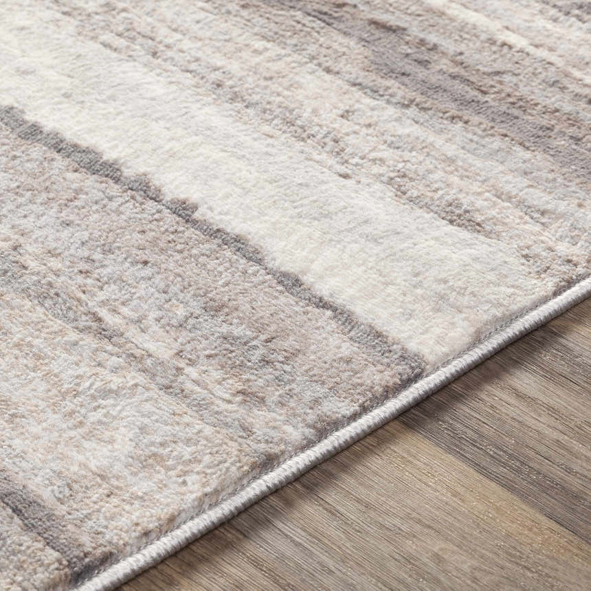 Close up of the Fombell Abstract Striped Area Rug showing charcoal, gray, tan, and white tones and soft texture. Texture
