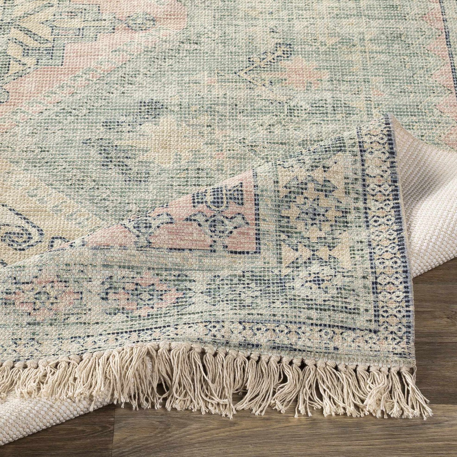 Close up of the Foraker Sage Green Cotton Rug showing its woven texture and bohemian pattern. Fold