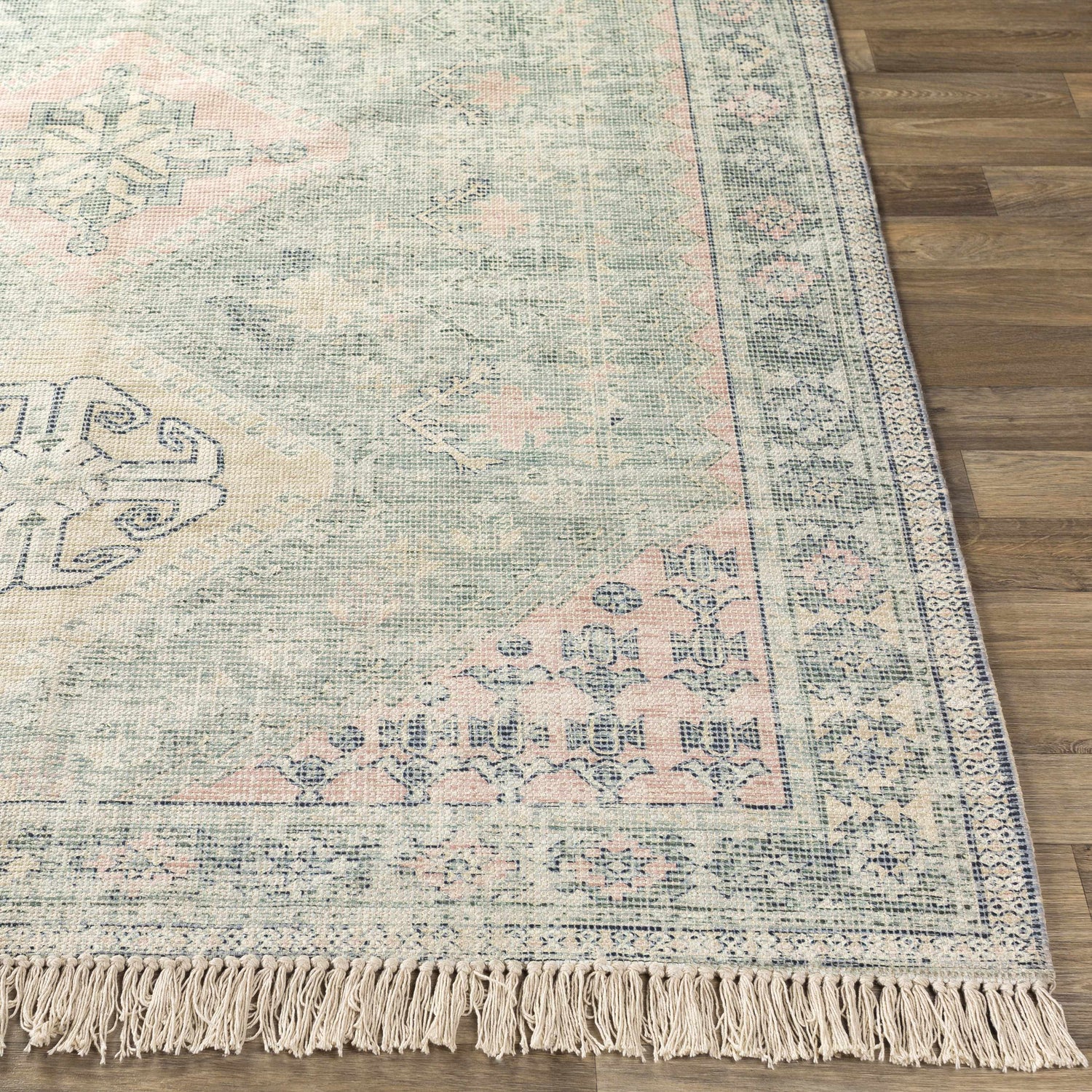 Close-up of the hand-woven Foraker Sage Green Cotton Rug, featuring a traditional bohemian pattern with pink, olive, and white hues. Front