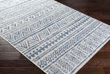 Close-up of Novato Navy rug showing bohemian all-over geometric pattern in blue and white on dark wood floors. Corner