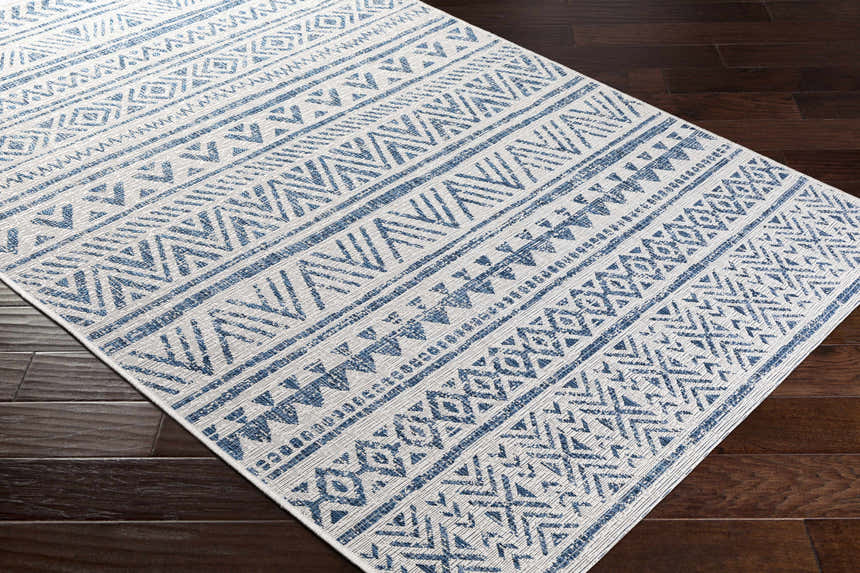 Close-up of Novato Navy rug showing bohemian all-over geometric pattern in blue and white on dark wood floors. Corner