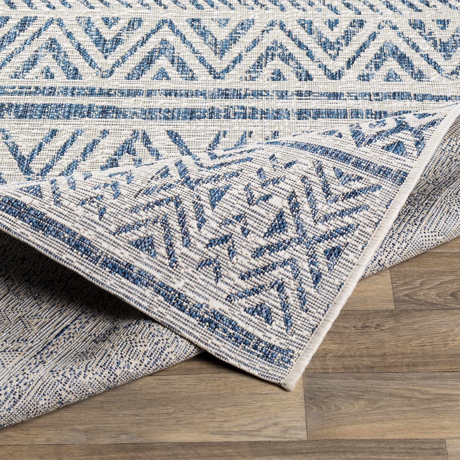 Close-up of the Novato Navy All Over Pattern Performance Rug showing its blue, light blue, and white geometric design. Fold