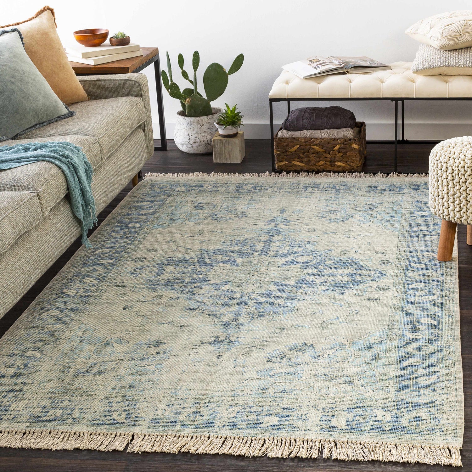Living room scene with a Fairlands Handmade Cotton-blend Rug in aqua and blue tones, styled with a sofa, bench, and plants. Roomscene-Rectangle