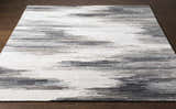 Close-up of the Farnhamville Area Carpet; a hand-tufted wool rug with a gray, white, and blue abstract pattern. Front