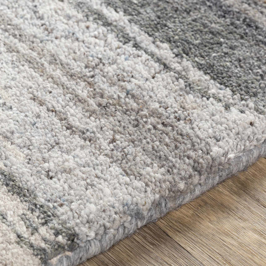 Close-up of the hand-tufted Farnhamville Area Carpet showing its wool texture and gray, white, and greige color palette. Texture