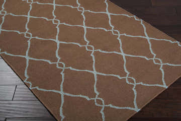 Close-up of the Frost Area Rug, a brown wool rug with a dusty sage geometric trellis pattern. Corner