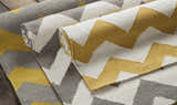 Close-up of the hand-woven Arvada Area Rug. Cream, mustard, and gray zigzags create a modern, geometric pattern. 100% wool texture. Styleshot