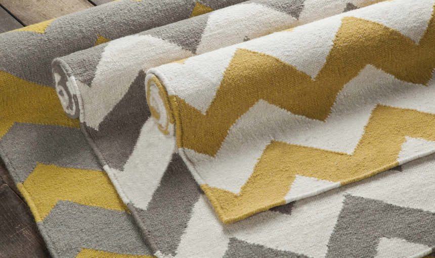 Close-up of the hand-woven Arvada Area Rug. Cream, mustard, and gray zigzags create a modern, geometric pattern. 100% wool texture. Styleshot