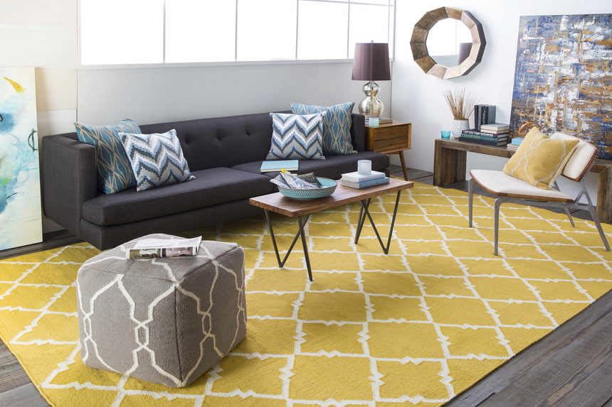 Living room scene with a mustard Bloomer Area Rug, gray sofa, wood furniture, and pops of blue and yellow accents. Roomscene-Rectangle
