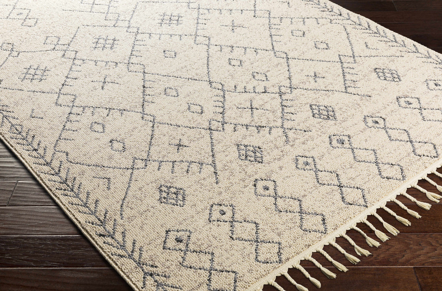 Close up of the ivory and tan Furman Area Rug, a farmhouse style runner with geometric patterns and tassels. Corner