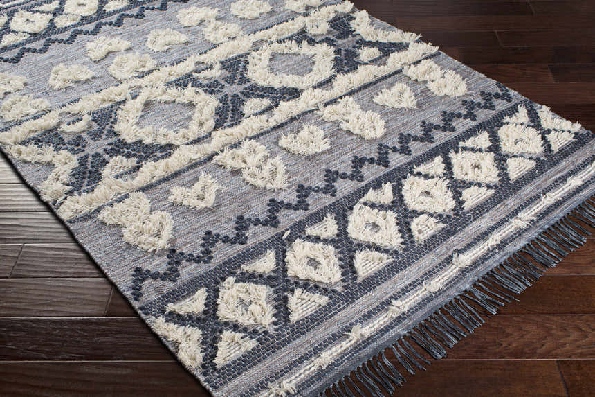 Close-up of Gakona High-Low Cream&Blue Wool Rug showing geometric pattern, cream shag accents, and dark blue details. Corner