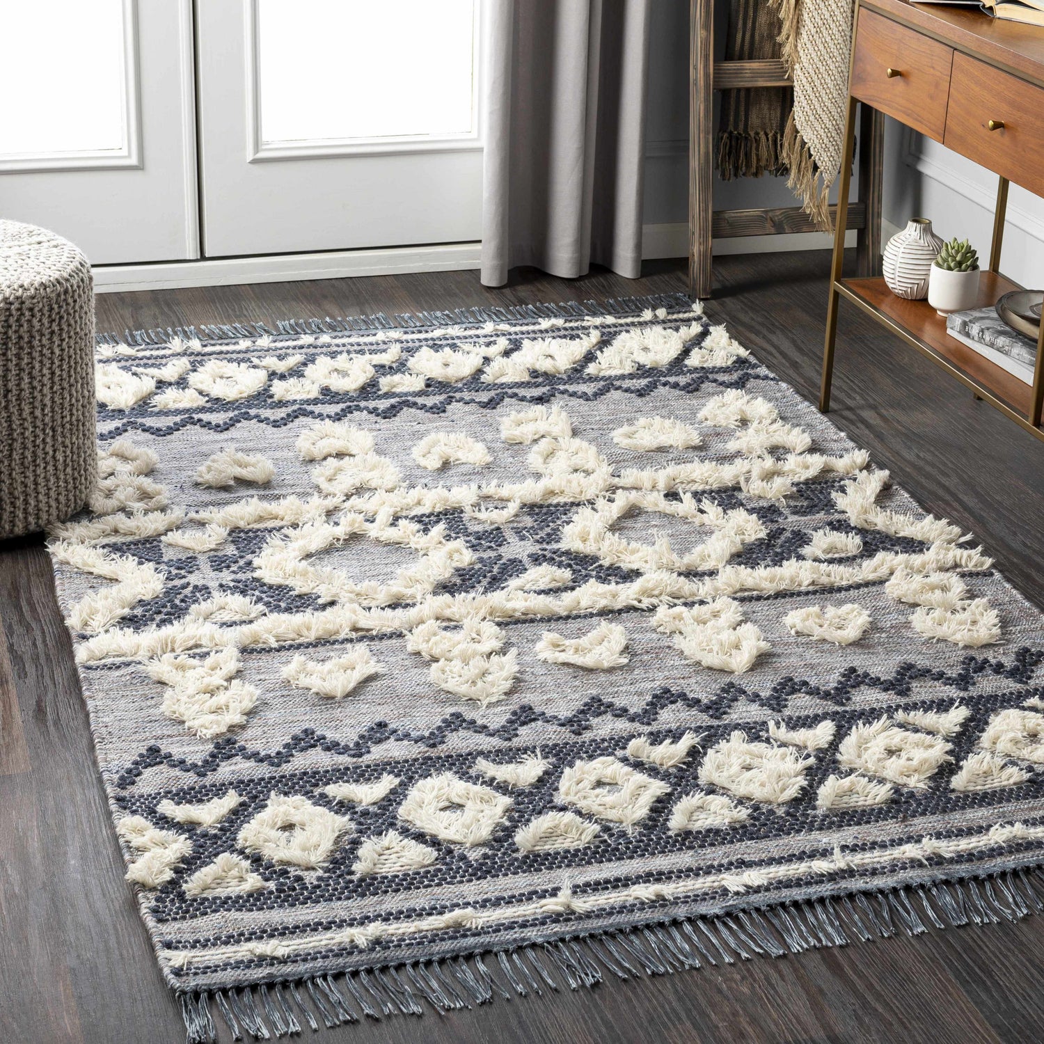 Living room scene with Gakona High-Low Cream&Blue Wool Rug. Bohemian style with cream pouf, wood console table. Roomscene-Rectangle