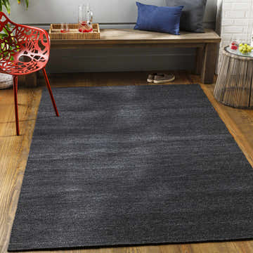 Contemporary patio scene with a charcoal Galiwinku Indoor & Outdoor Rug, wooden bench, and red chair. Roomscene-Rectangle