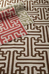 Close-up of Garnavillo Area Rug. Hand-woven wool rug with a geometric pattern in beige, brown, rose, and green. Styleshot