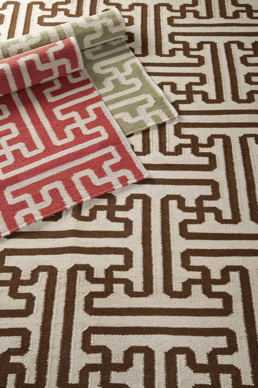 Close-up of Garnavillo Area Rug. Hand-woven wool rug with a geometric pattern in beige, brown, rose, and green. Styleshot