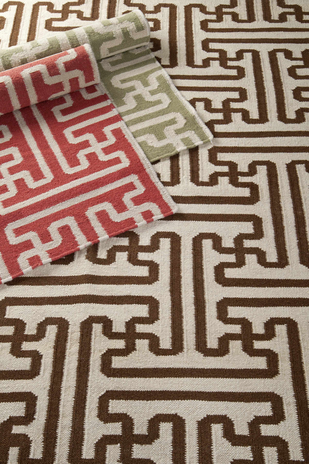 Close-up of Garnavillo Area Rug. Hand-woven wool rug with a geometric pattern in beige, brown, rose, and green. Styleshot