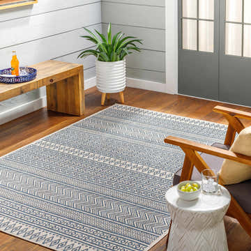 Sunroom scene with a Madras Ink All Over Performance Rug, wood bench, potted plant, and chair. Roomscene-Rectangle
