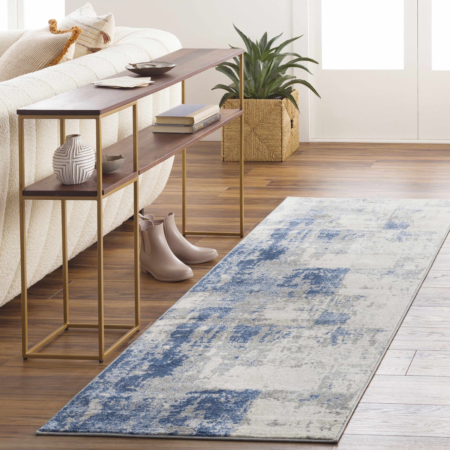 Living room scene with a denim and gray Gerton Area Rug runner, textured sofa, and wood console table. Roomscene-Runner