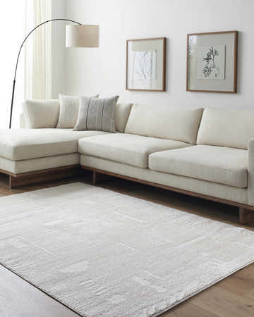 Living room scene with ivory Winda Area Rug, neutral sectional sofa, and minimalist wall art. Roomscene-Rectangle