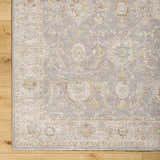 Close-up of Giang Thick Luxe Area Rug in beige and gray with traditional floral pattern on light wood floor. Corner
