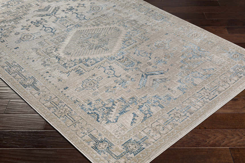 Close-up of the Girikbedro Area Carpet. Cream and light beige rug with a traditional, vintage-inspired blue pattern. Corner
