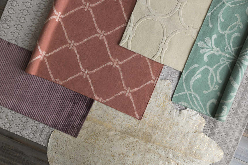 Close-up of Hazelhurst Area Carpet in dusty pink with a geometric pattern, light gray, and other rug samples. Styleshot