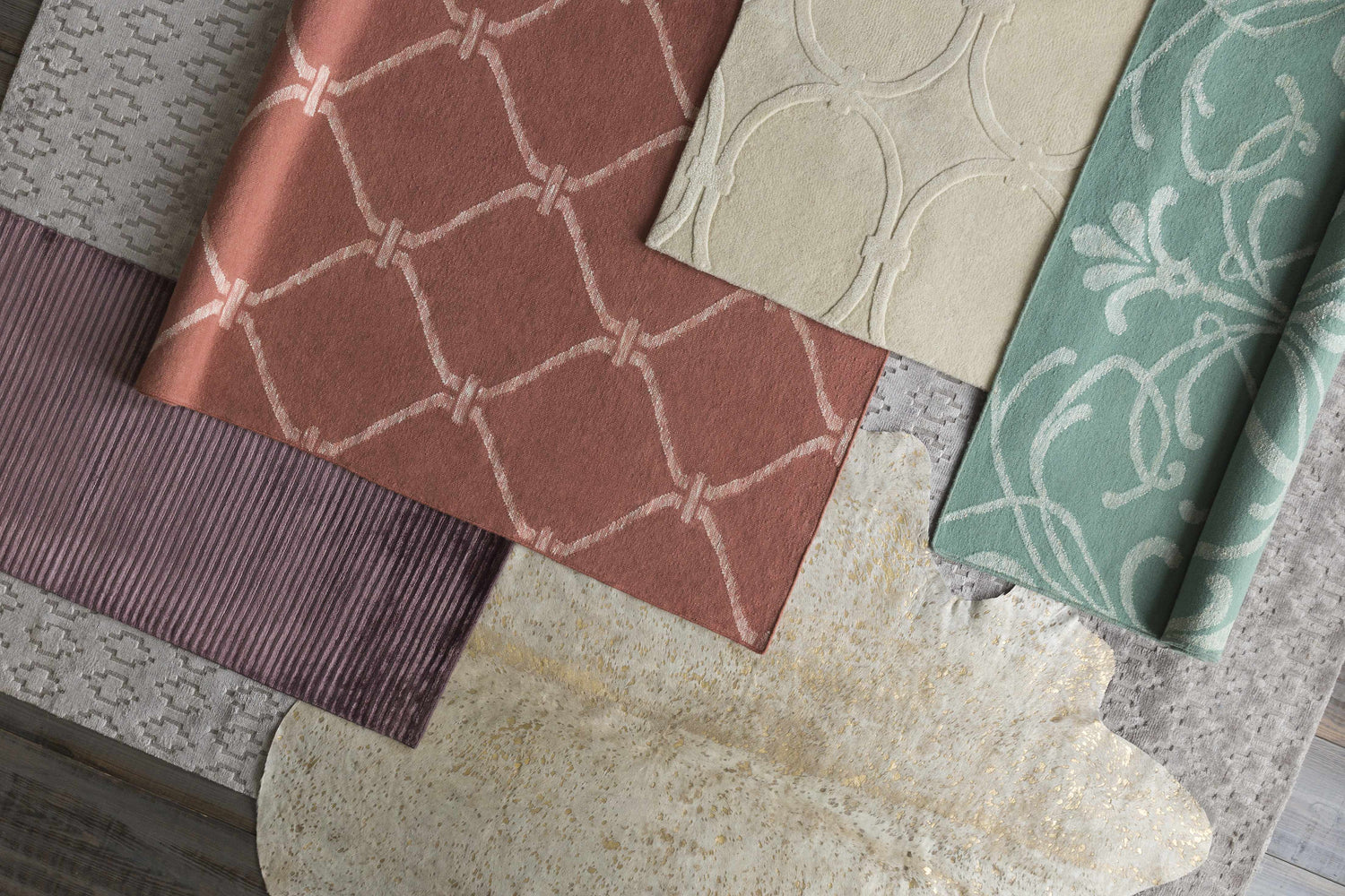 Close-up of Hazelhurst Area Carpet in dusty pink with a geometric pattern, light gray, and other rug samples. Styleshot