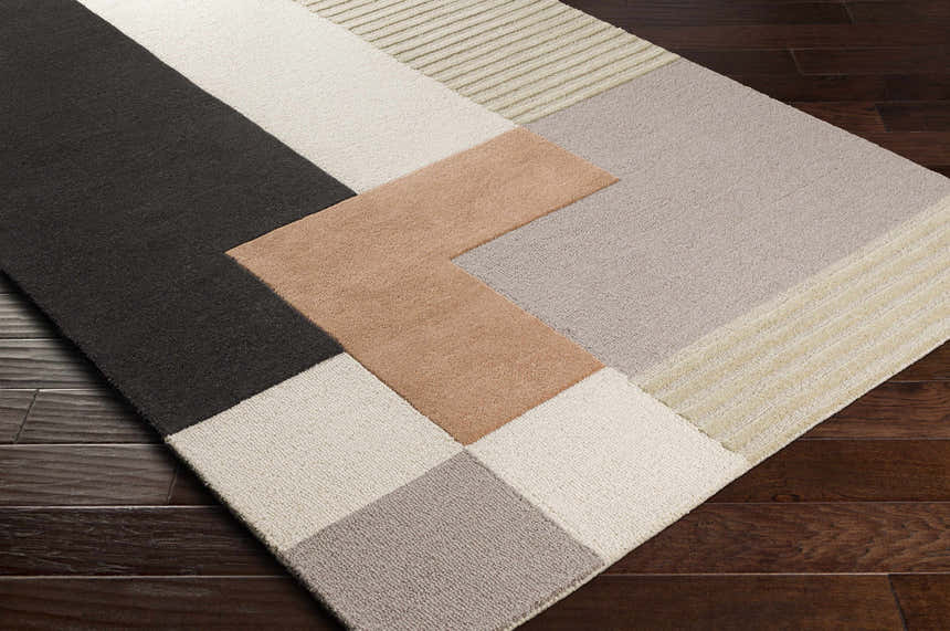 Close-up of the Glenmavis Area Rug. Geometric design in black, beige, gray, peach, and tan wool. Hand-tufted texture. Corner