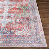 Close-up of the Rust Goma Vintage Area Rug showing its blush, red, blue, and cream bohemian pattern on a wood floor. Front