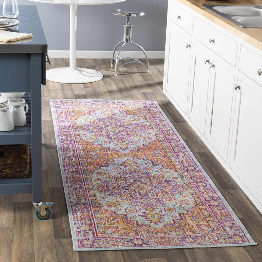 Kitchen scene with a Grelton rug runner in burgundy, lavender, mustard, and yellow. White cabinets, blue island, and wood floors. Roomscene-Runner