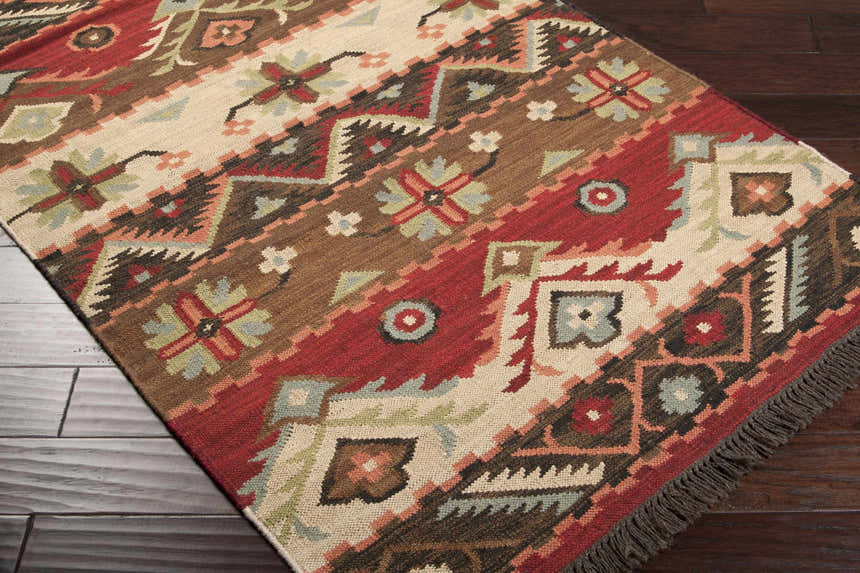 Close-up of the hand-woven Grimsby Wool Area Rug, featuring bohemian-style geometric patterns in burgundy, brown, and beige. Corner
