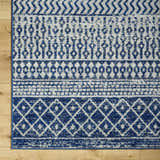 Close-up of the Constantin Blue Area Rug showing its bohemian-inspired geometric patterns in blue, gray, and white. Swatch