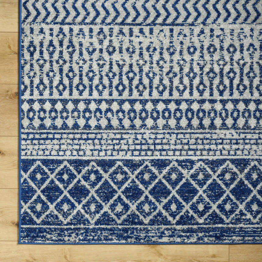 Close-up of the Constantin Blue Area Rug showing its bohemian-inspired geometric patterns in blue, gray, and white. Swatch