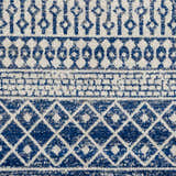 Close-up of the Constantin Blue Area Rug. Features a bohemian-inspired geometric pattern in shades of blue, gray, and white. Texture