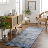 Entryway with Constantin Blue Area Rug, wood console table, wicker chair, plants, and light hardwood floors. Roomscene-Runner