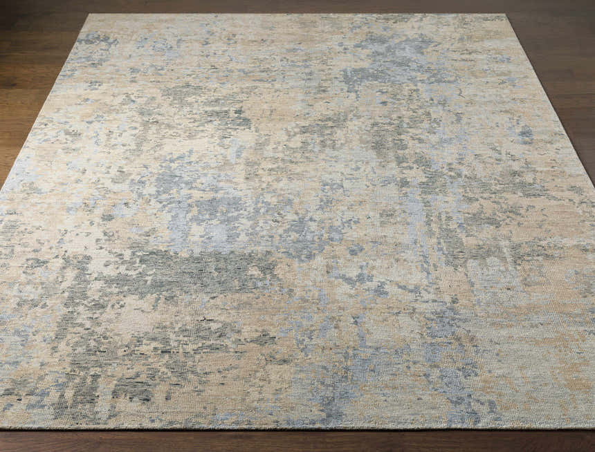 Close-up of a Greenhills Handmade Wool Area Rug. Beige rug with abstract charcoal, blue, and taupe pattern. Front