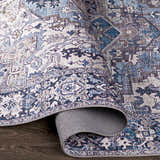 Close-up of the Neyland Iris Blue Area Rug. Features a traditional, bohemian pattern in cream, blue, and mauve tones. Fold