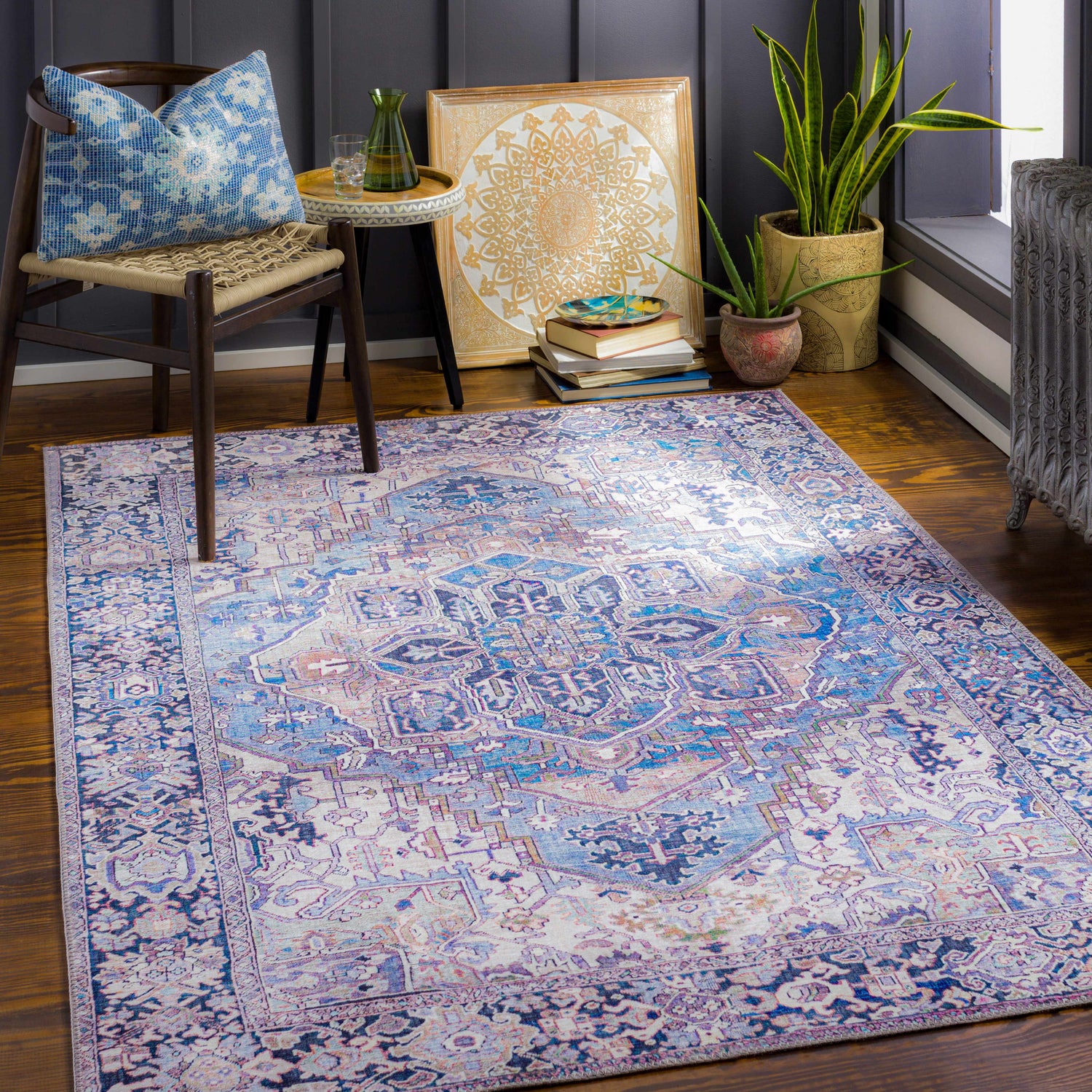Cozy room scene with the Neyland Iris Blue Area Rug, chair, side table, plants, and dark blue accent wall. Roomscene-Rectangle