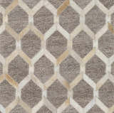 Close-up of the Haddix Premium Leather Rug. Features a geometric pattern in beige, cream, and light brown hair on hide. Texture