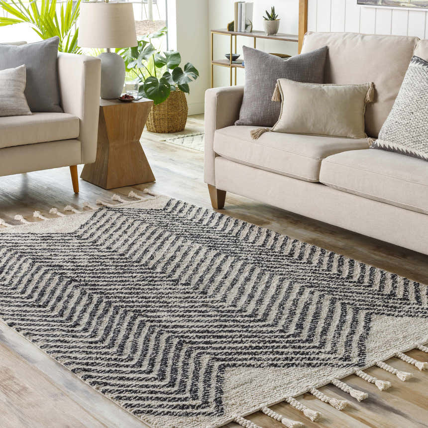 Living room scene with a charcoal and cream Halton Area Carpet, beige sofa, and light wood floors. Roomscene-Rectangle