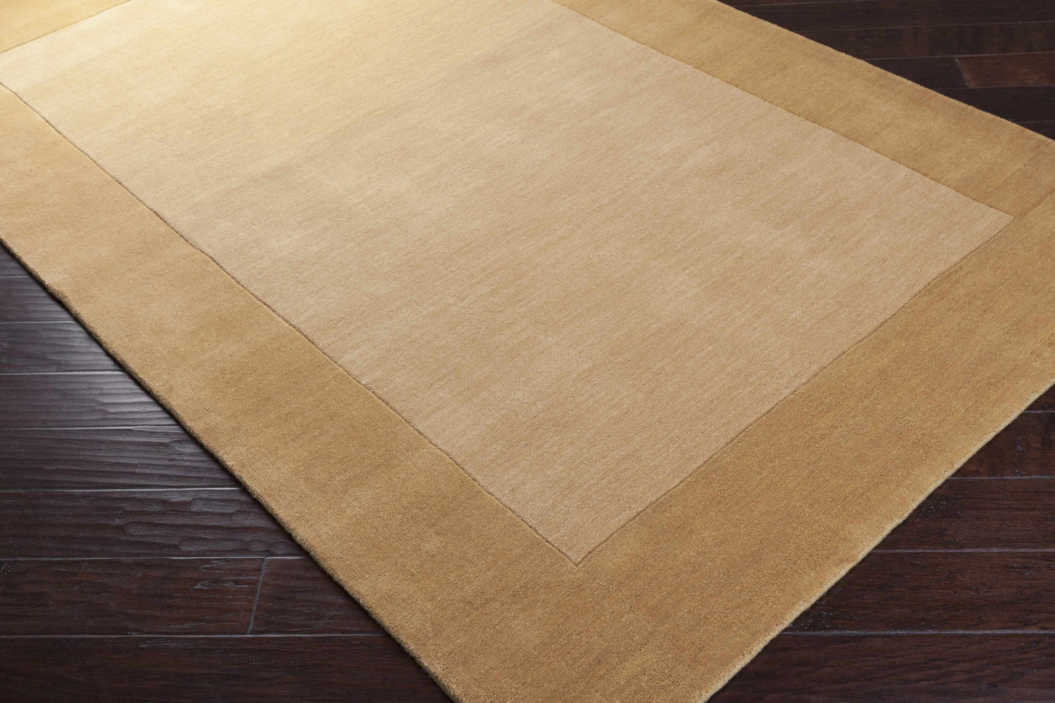 Close-up of a Bordered Solid Camel Yellow Wool Rug showing its texture and color on dark wood flooring. Corner