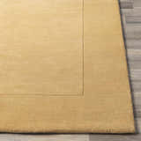 Close up of a Bordered Solid Camel Yellow Wool Rug showing texture and border detail. Front