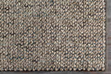 Close-up of the hand woven Hansell Area Rug. Charcoal, ivory, and ice blue wool rug with a textured, contemporary design. Corner