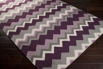 Close-up of a hand woven Hardwood Area Rug. Contemporary chevron pattern in dark brown, gray, ivory, mauve, and plum. Corner