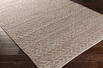 Close-up of the hand-woven Harlingen Area Rug. Brick red and gray geometric pattern on dark wood floors. Farmhouse style. Corner