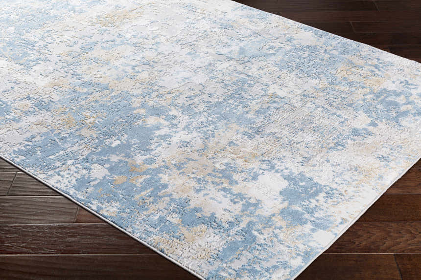 Close-up of the Hawes Faux Silk Rug in light blue, light gray, mustard, and off white on dark wood flooring. Abstract design. Corner