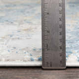 Close up of Hawes Faux Silk Rug showing texture and pile height with a ruler. Colors include light blue, gray, and mustard. Pile