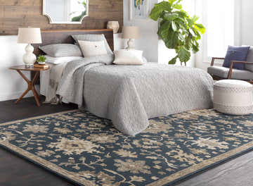Bedroom scene with a navy floral Caesar 1154 Wool Rug, gray bedding, wood accents, and a neutral color palette. Roomscene-Rectangle