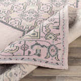 Close up of Hickson Carpet - Clearance. Hand knotted rug with a traditional design in charcoal, light pink, oatmeal, pale pink, and slate. Fold